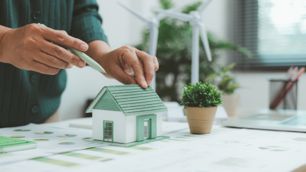 Homme avec une chemise verte tenant un stylo vert, devant une maquette de maison verte