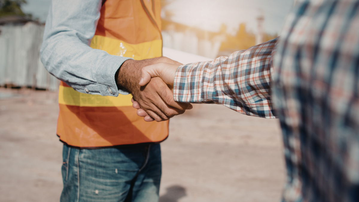 Poignée de main sur un chantier entre un professionnel du bâtiment et un homme avec une chemise